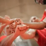 Groupe de personnes unies les mains au centre, symbole de motivation collective?