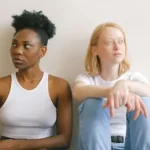 Deux jeunes femmes assises côte à côte, tournées l’une de l’autre, symbolisant une relation conflictuelle ou toxique